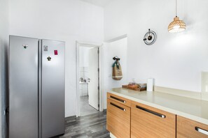 Une cuisine moderne dotée d’appareils électroménagers en acier inoxydable, de meubles en bois et d’un luminaire suspendu.
