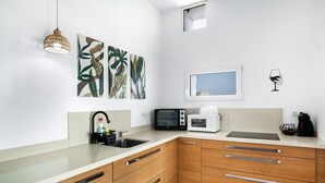 Een moderne keuken met een magnetron, koffiezetapparaat en een hangende lamp.