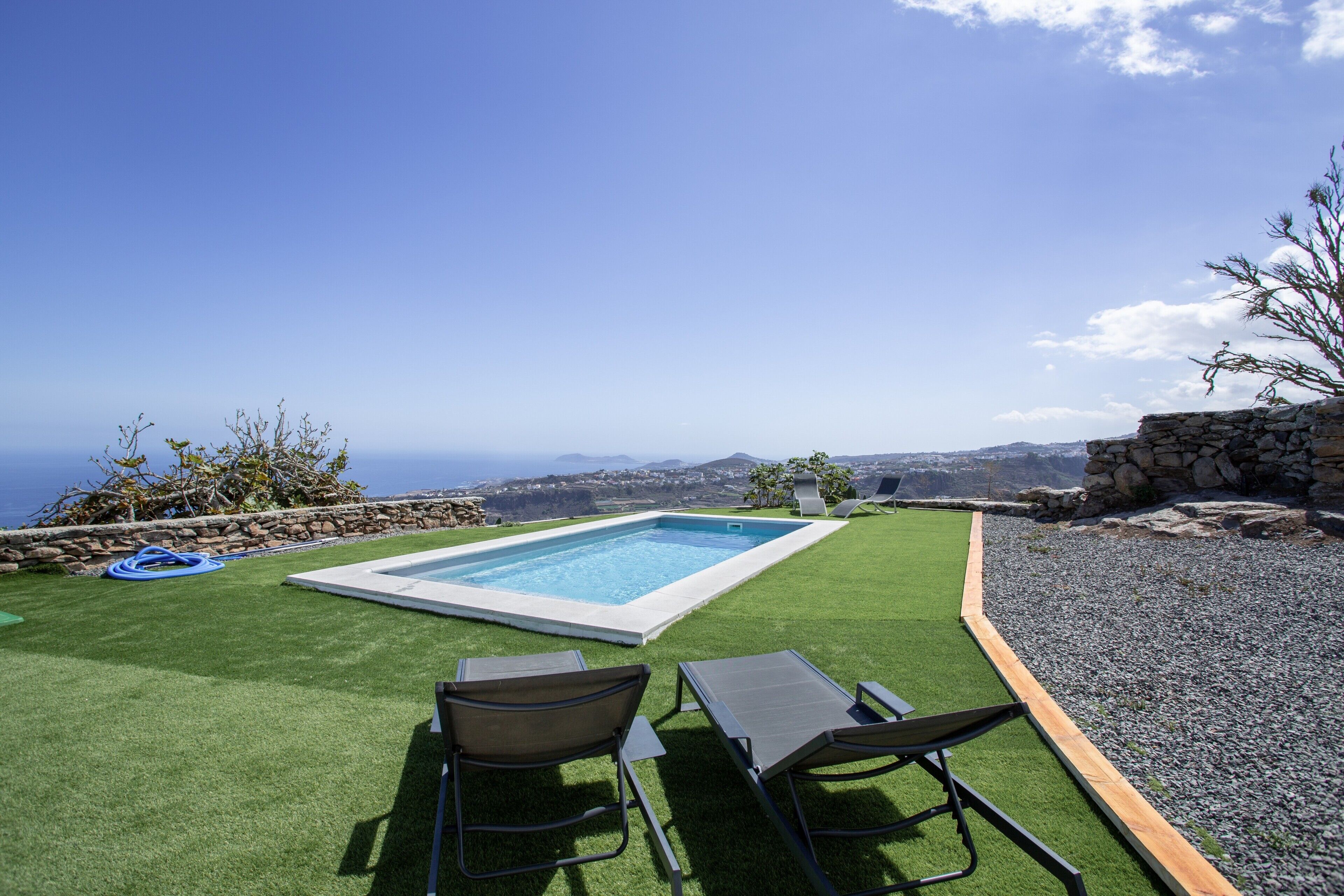Una piscina con dos sillas de descanso y vista al océano.