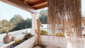 Un espacio al aire libre techado con techo de madera, macetas de piedra y una rama colgante.