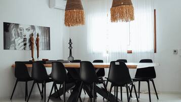 A modern dining area with a wooden table, black chairs, and two hanging woven light fixtures.