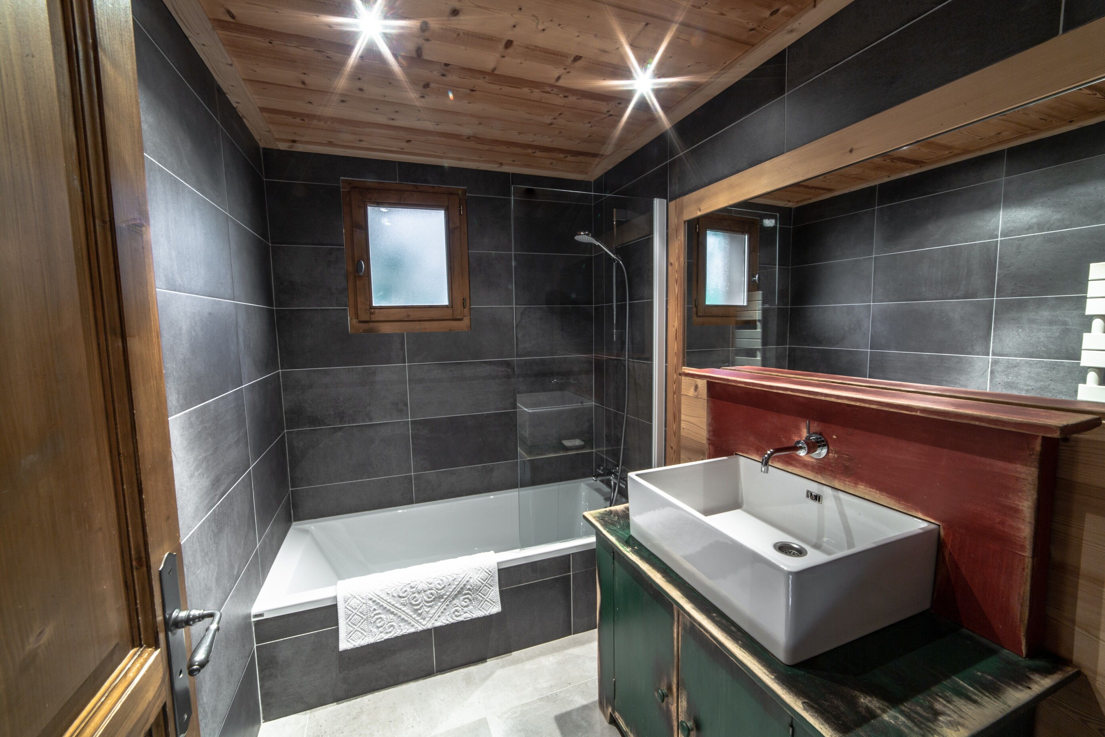 A modern bathroom with a bathtub, a sink, and a large mirror.