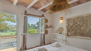 A bedroom with a large bed, a window with curtains, a hanging basket, and a wall with decorative items. - Villa "Amigo Near Las Dalias - Nice" (Illes Balears)