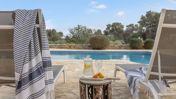 A poolside area with lounge chairs, a table with a pitcher and glasses, and a view of the pool and surrounding greenery. - Villa "Amigo Near Las Dalias - Nice" (Illes Balears)