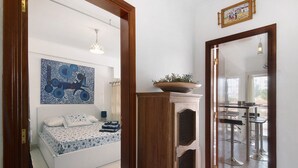 Ein Schlafzimmer mit einem Bett, einem Wandbild, einer Zimmerpflanze und einer Essecke mit Barhocker.