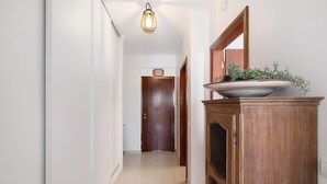 Ein Flur mit einer Holztür am Ende, einer Leuchte darüber und einer großen Schüssel auf einem Holzschrank.