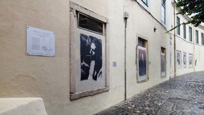 Une rue pavée bordée d’un bâtiment où sont affichées des affiches et où se trouve un panneau d’affichage.