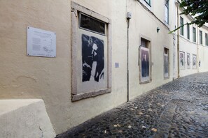Une rue pavée bordée d’un bâtiment où sont affichées des affiches et où se trouve un panneau d’affichage.