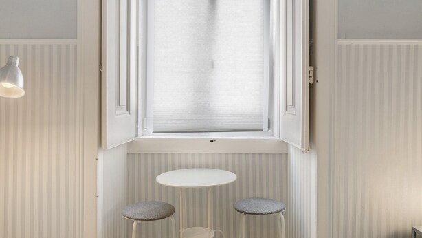 Une pièce avec une fenêtre, une table et deux tabourets.