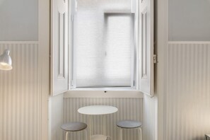 A room with a window, a table, and two stools. - Apartment 'Mouraria Flat Studio By Insighthome' with Wi-Fi (Lisboa)