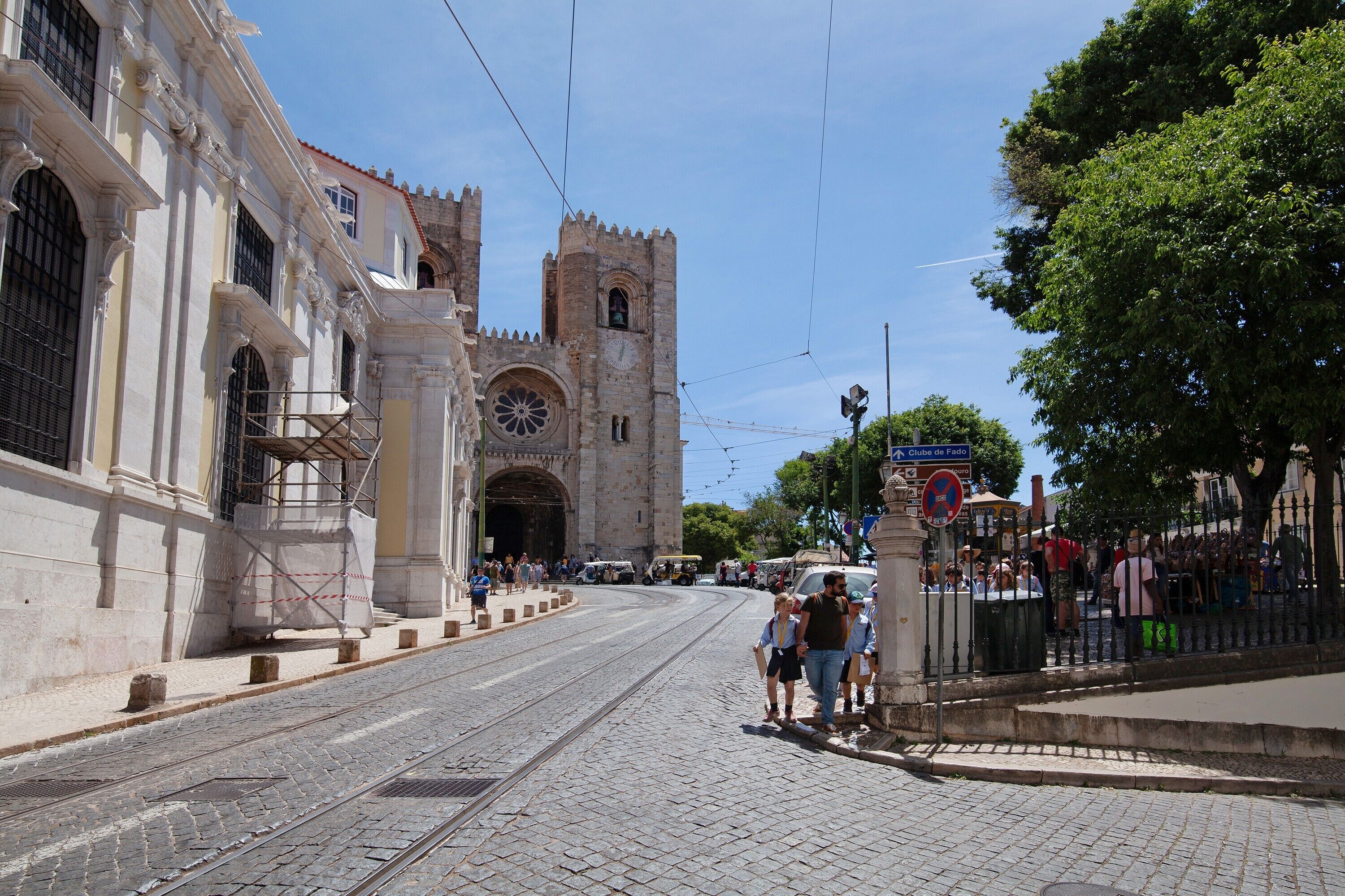 A historic building with a large arched entrance, a clock tower, and a tram line.
