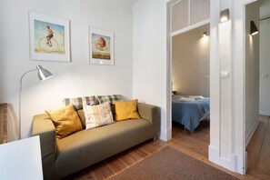 A living room with a sofa, a lamp, and two framed pictures on the wall.
