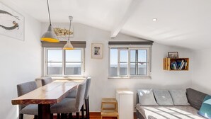 A cozy room with a wooden dining table, grey upholstered chairs, a grey sofa, and a small white cabinet.