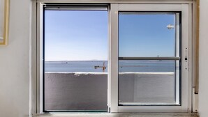 A window with a view of a body of water and a distant landmass.