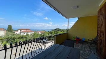 Ein Balkon mit Blick auf das Meer und Gebäude, ein Tisch mit Kerze sowie ein Stuhl.