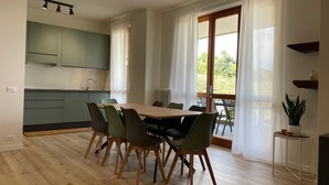 Een moderne keuken met een eethoek, houten vloeren en uitzicht op groen.