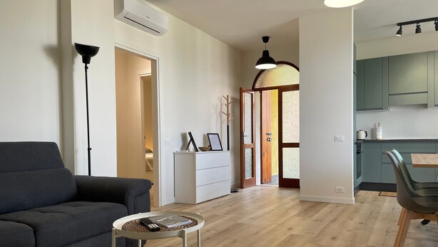 Een moderne woonkamer met een bank, een klein rond tafeltje en een eethoek met een stoel.