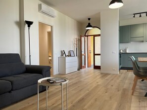 Una sala moderna con un sofá, una mesita redonda y una zona de comedor con una silla.