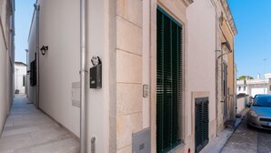 Eine enge Straße mit einem Gebäude, das eine Treppe, eine Tür und ein Fenster mit Rollläden zeigt.