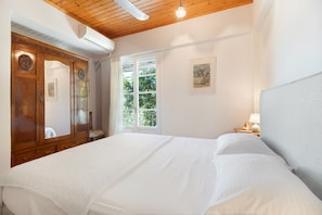 Une chambre avec un grand lit, une armoire en bois et une fenêtre donnant sur un paysage verdoyant.