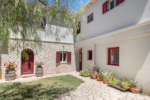 Un edificio in pietra con una porta rossa, piante in vaso e un vialetto in pietra.