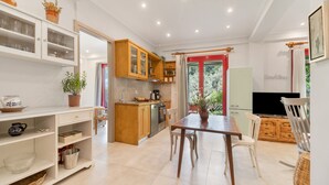 Una cocina moderna con muebles blancos, una mesa de comedor y un televisor.