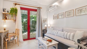 Una sala de estar moderna con un sofá, una mesa de comedor, una silla y un ventanal corredera que da a un jardín.
