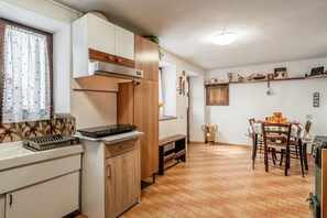 Cozinha compacta com armários de madeira, forno embutido e área de jantar com mesa e cadeiras.