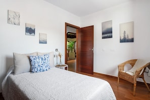 A bedroom with a bed, a chair, and wall art.