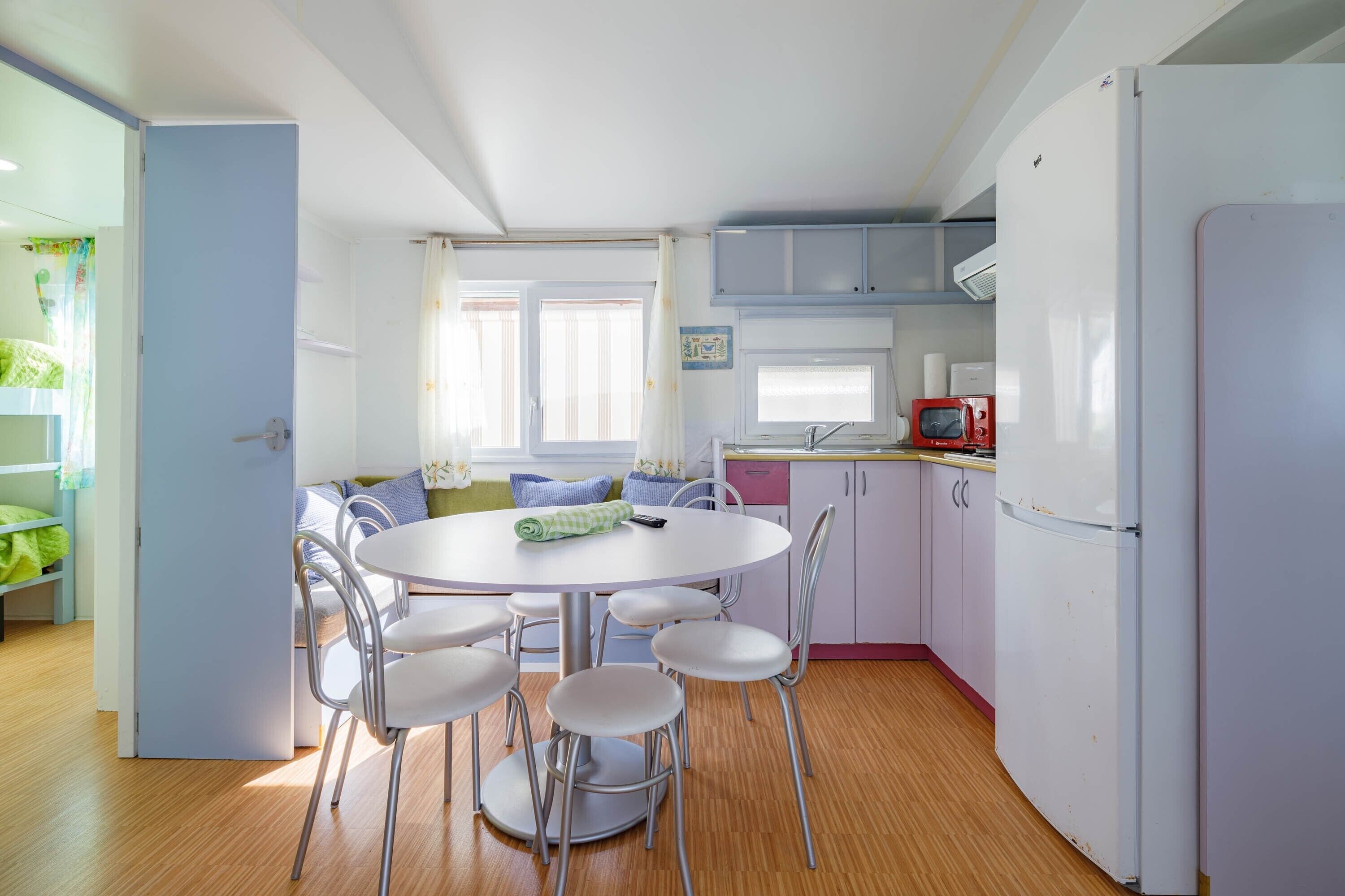 Una cocina compacta con una mesa de comedor, sillas, un refrigerador y un microondas.