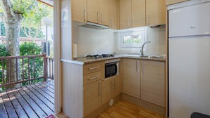 Eine kompakte Küche mit Holzausstattung, einem Backofen, einer Mikrowelle und einem Kühlschrank.