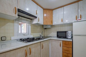 A kitchen with white cabinets, a microwave, a refrigerator, a window, and a gas stove. - Bungalow 'B' with Private Pool, Private Terrace and Wi-Fi (Pontevedra)