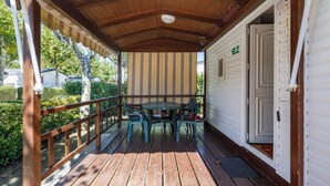A covered porch with a wooden deck, a round table with chairs, and a white door with the number 82. - Bungalow 'B' with Private Pool, Private Terrace and Wi-Fi (Pontevedra)