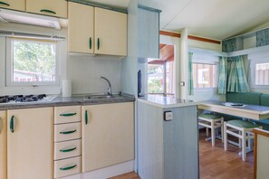 A compact kitchen with a sink, stove, and dining area with chairs.