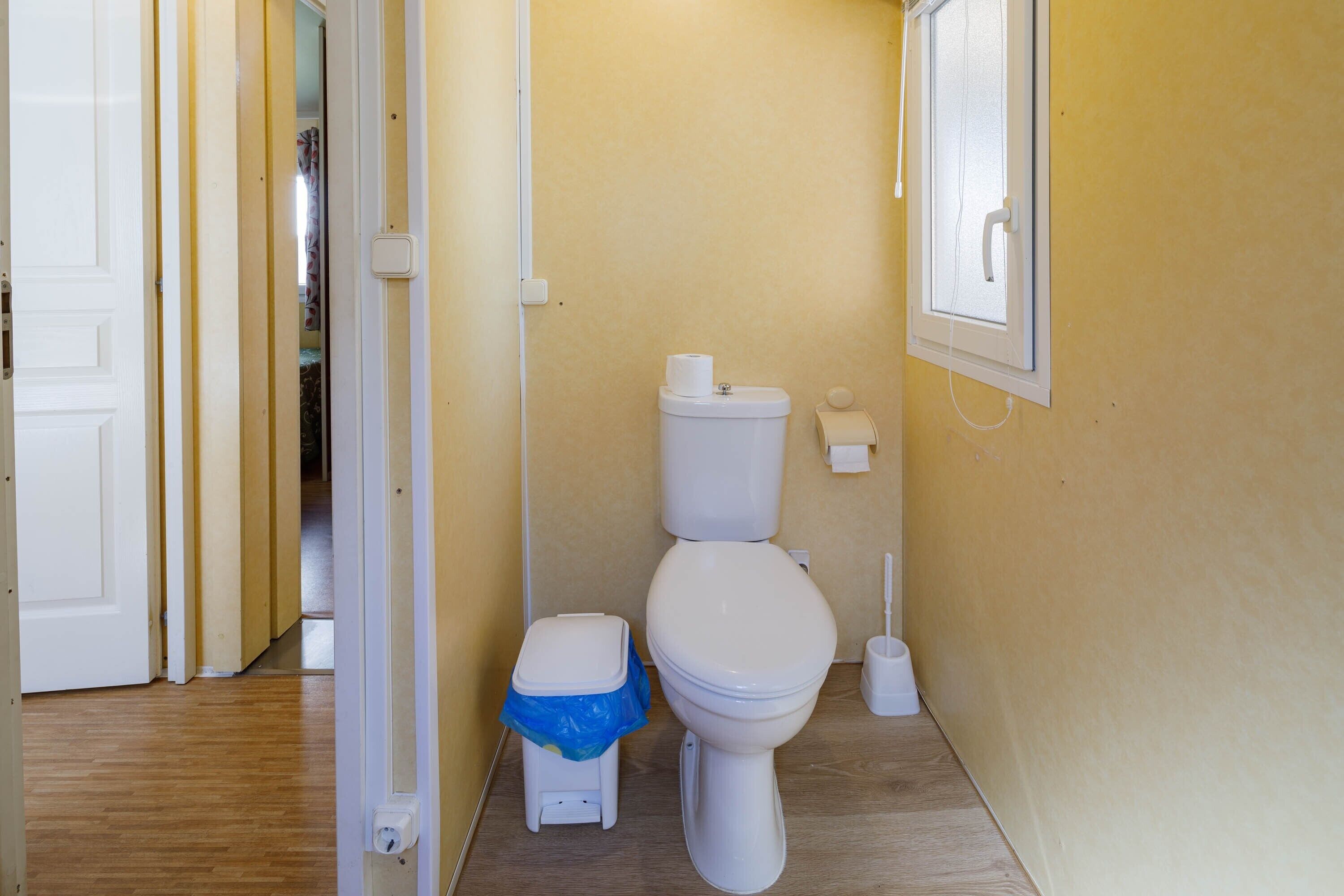 Ein Badezimmer mit Toilette, Mülleimer und einem Händetrockner.