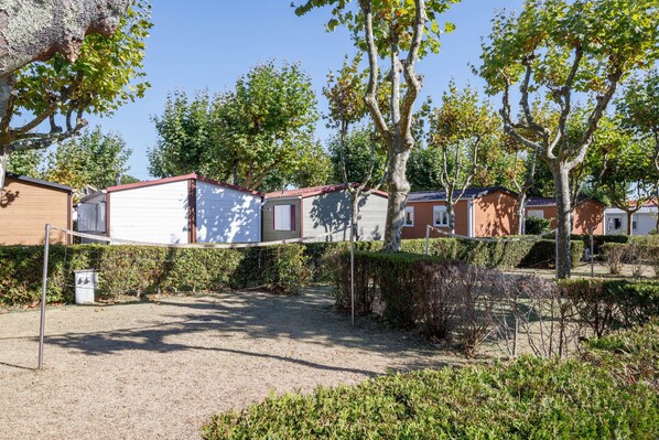A row of mobile homes with a gravel path and greenery in the foreground.