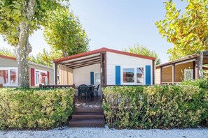 A mobile home with a covered porch, a table with chairs, and a gravel driveway.