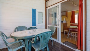 A covered outdoor dining area with a table and chairs, a sliding glass door leading to a kitchen, and a wooden ceiling. - Bungalow 'D' with Private Pool, Private Terrace and Wi-Fi (Pontevedra)