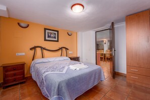 A bedroom with a bed, wooden wardrobe, and a bathroom visible through an open door.