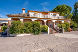 A two-story building with a balcony, a staircase, and a paved driveway.
