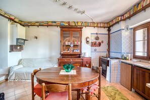 A dining area with a wooden table and chairs, a cabinet with glass doors, and a kitchen area with a sink and countertop. - Apartment 'Col Di Metino' with Mountain View, Private Garden and Wi-Fi (Gualdo Tadino)
