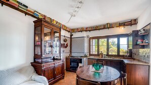 A kitchen with a dining table, wooden cabinets, and a window. - Apartment 'Col Di Metino' with Mountain View, Private Garden and Wi-Fi (Gualdo Tadino)