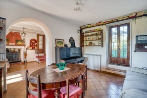 A dining area with a wooden table and chairs, a television, and a bookshelf with various items. - Apartment 'Col Di Metino' with Mountain View, Private Garden and Wi-Fi (Gualdo Tadino)
