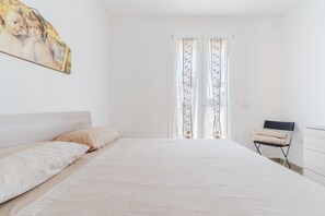 Une chambre à coucher avec un lit, des oreillers, une chaise et un tableau accroché au mur.
