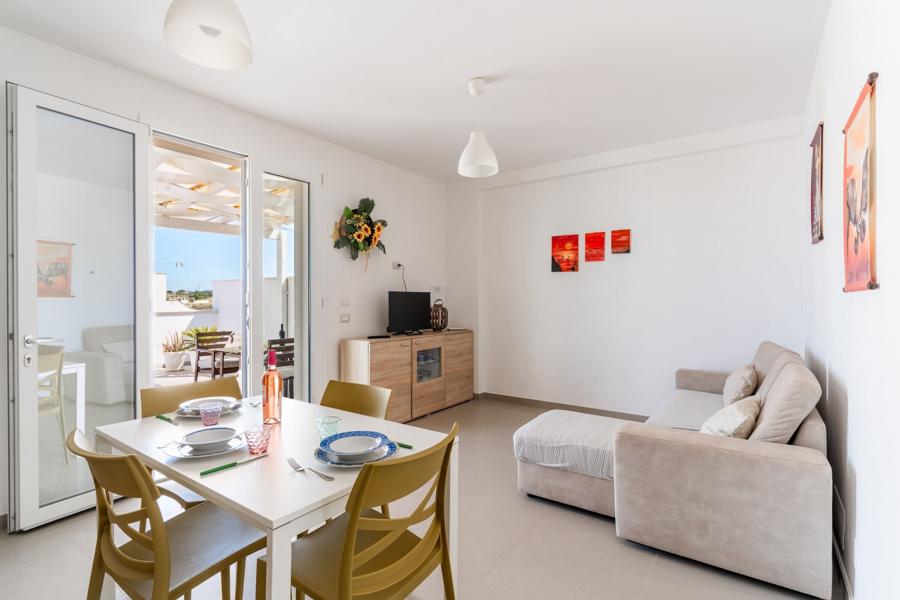Una sala de estar moderna con una mesa de comedor, un sofá y un televisor sobre un mueble de madera.