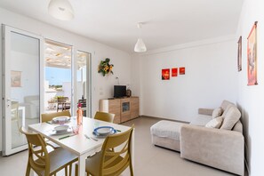 Un salon moderne avec une table à manger, un canapé et un téléviseur posé sur un meuble en bois.
