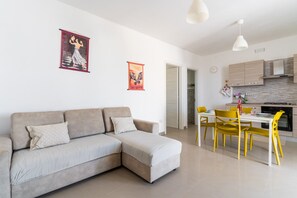 Un salon moderne comprenant un canapé, une table à manger, des chaises et un coin cuisine.