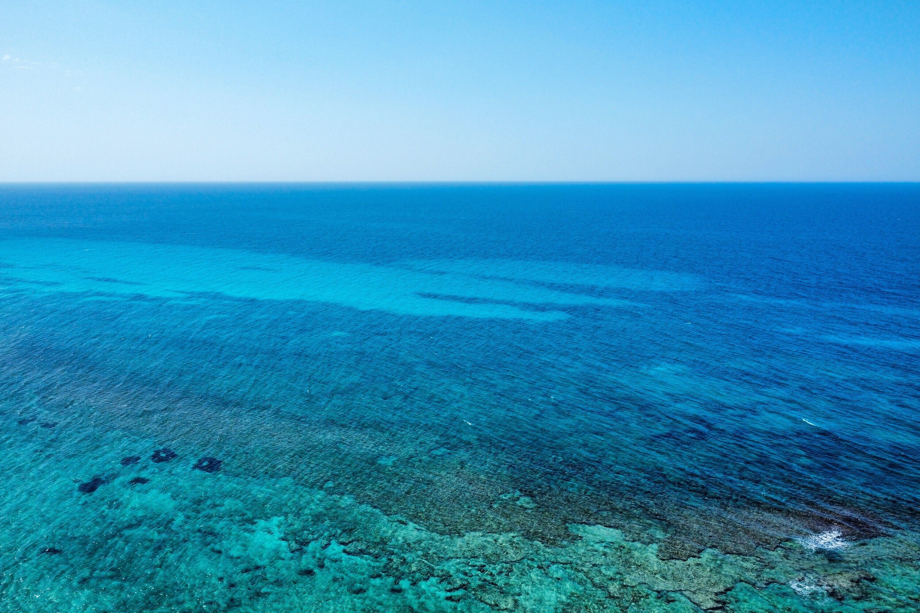 Une vue dégagée sur une zone côtière, avec un récif corallien et une mer calme.