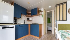 Una cocina compacta con armarios azules, un lavavajillas blanco y un microondas.