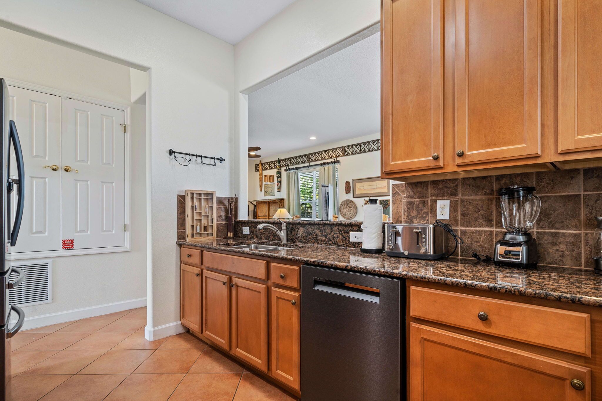 A kitchen with wooden cabinets, a granite countertop, a dishwasher, a toaster, and a blender.
